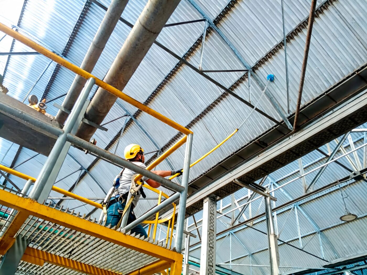 Operario de Proverclean con arnés limpiando la estructura de una planta en altura